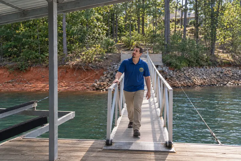 George Karampoulis walking down an aluminum gangway to a covered boat dock, one hand on the rail